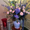 Blue hydrangea, blue delphinium and white roses arranged beautifully in a white
