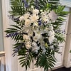 Palm leaves circling white roses and mums with blue delphinium all the