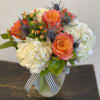 A lush arrangement of white cloud hydrangea, coral roses and hypericum with