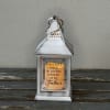 A white lantern with a battery operated candle.

Text Reads: &quot;This light shines