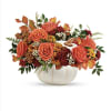 white ceramic pumpkin filled with fall colored  flowers and foliage 