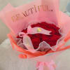 A charming bouquet of deep red roses wrapped in soft pink paper