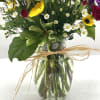 A mix of fall hues in a clear, glass vase finished off