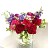 This vibrant flower arrangement features a lush mix of red roses, bright