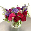 This vibrant flower arrangement features a lush mix of red roses, bright