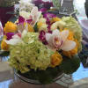 Tropical twist on a classic, low, and full arrangement of orchids, roses