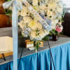 White roses, chrysanthemum, carnations, Blue hydrangea and leather leaf greens. Sky blue