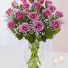 Lavender Roses with Limonium and seasonal greens in Clear vase 8&rdquo; H
Standard