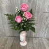 A cute pink and white floral arrangement inside of a ceramic ballet
