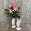 A cute pink and white floral arrangement inside of a ceramic ballet