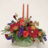 Ceramic pumpkin with lid is arranged with red gerbera daisies, orange roses