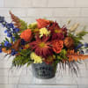 A fall floral arrangement with features a warm, earthy color palette inspired