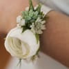 Cuff corsage featuring ranunculus with bits of foliage and other filler flowers.
