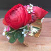 Cuff corsage featuring ranunculus with bits of foliage and other filler flowers.