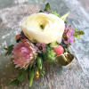 Cuff corsage featuring ranunculus with bits of foliage and other filler flowers.