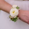 Cuff corsage featuring ranunculus with bits of foliage and other filler flowers.