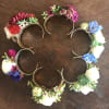 Cuff corsage featuring ranunculus with bits of foliage and other filler flowers.