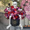 Large beautiful arrangement of burgundy and pink flowers with a sitting skeleton