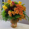 A lush assortment of fall flowers arranged in a festive mason jar.
