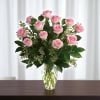 A dozen beautiful pink roses, with lush greenery in a vase 