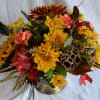 A brushed silver footed compote full of fall flowers in a warm
