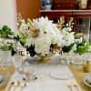 This beautiful all white floral centerpiece accented with a gold base can