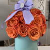 Orange roses in a light teal box with a purple bow. 