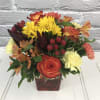 Bright orange cube overflowing with bright autumn oranges and yellows. Roses, carnations