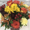Bright orange cube overflowing with bright autumn oranges and yellows. Roses, carnations