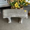 A concrete bench with ivy leaves and vines.  The bench and