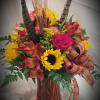 A traditional arrangement of roses, sunflowers asters, alstroemeria and other flowers accented