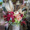 A mix of roses, hydrangea, and orchids with seasonal accents in a