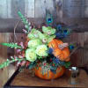 Lush roses, orchids, snapdragons, and thistles arranged in a ceramic pumpkin, accented