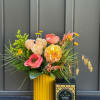 A seasonal gift set including a fall arrangement and a 9.5 oz