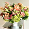 A gorgeous flower arrangement in a ceramic white compote vase, filled with