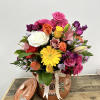  Nestled in a handcrafted clay pot, this vibrant bouquet features an