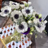 This exquisite arrangement features striking anemones alongside lush textures of eucalyptus and