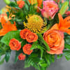 A monochromatic mix of oranges that includes pin-cushion protea, free spirit roses