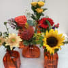 Six charming assorted orange colored vases, each accented with a different flower