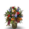 This vibrant arrangement overflows with rich seasonal color, blending roses, lilies, delphinium