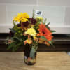 A frosted pumpkin mason jar filled with fresh fall colored flowers. 