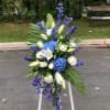 A standing spray of blue and white flowers. Consisting of hydrangea, lilies