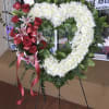 This exquisite solid heart standing spray in stunning whites, including red roses
