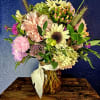 Beautiful vased arrangement featuring sunflowers  amidst many other complementary flowers. 