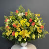 A graceful tribute featuring elegant lilies, vibrant orange roses, and cheerful yellow