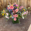 An arrangement of in season pink, yellow and touches of blue blooms.