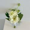 Elegant and timeless, this boutonniere pairs delicate white blooms with fresh greenery