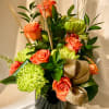 Bold oranges and green seasonal blooms in a custom vase.