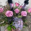 Lavender roses and seasonal blooms in a custom vase with a witch