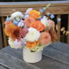 Flower arrangement with soft autumn colors, with a pop of orange and